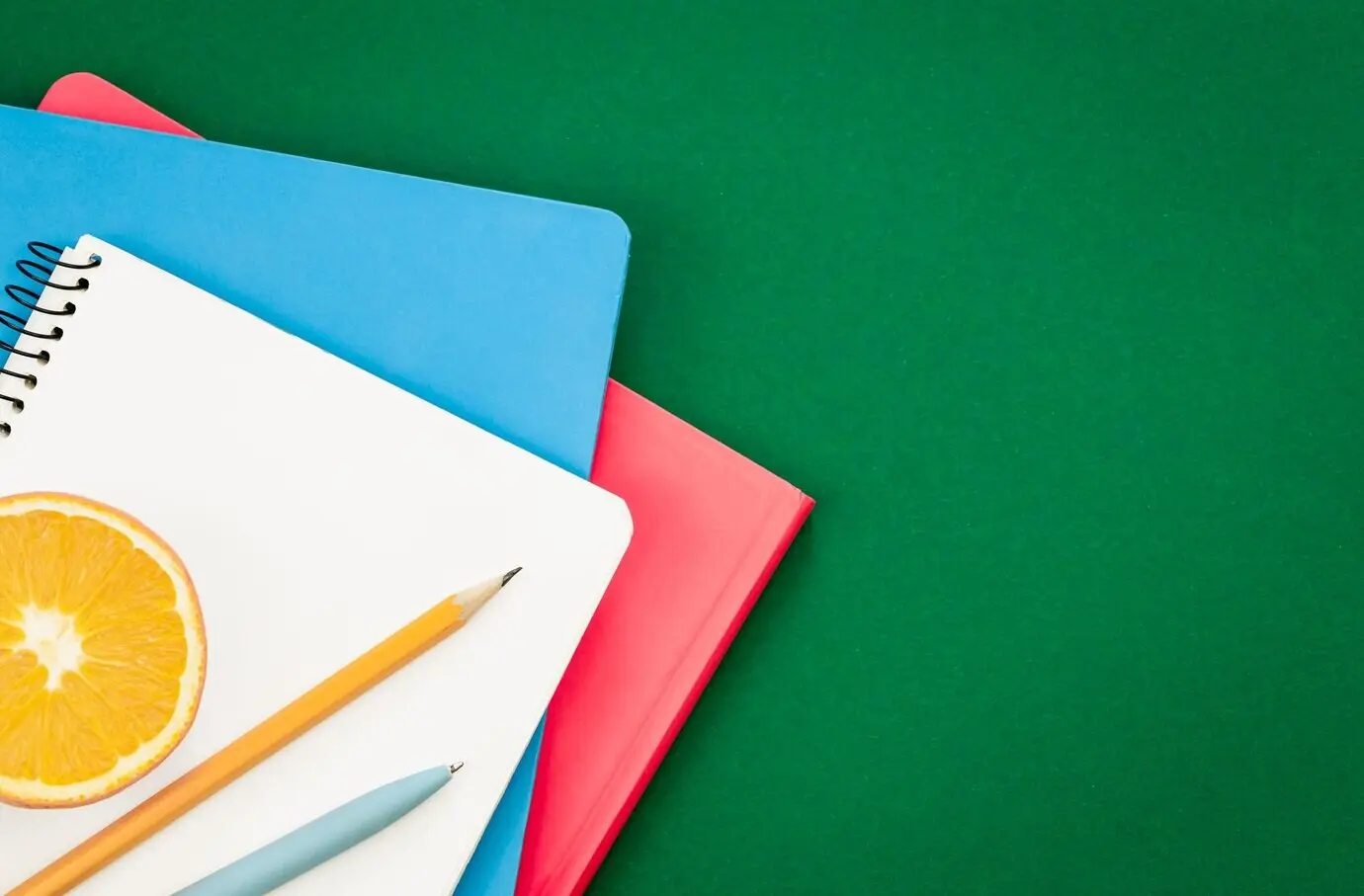 Flatlay mit Notizbüchern auf grünem Hintergrund zum Thema Schule.